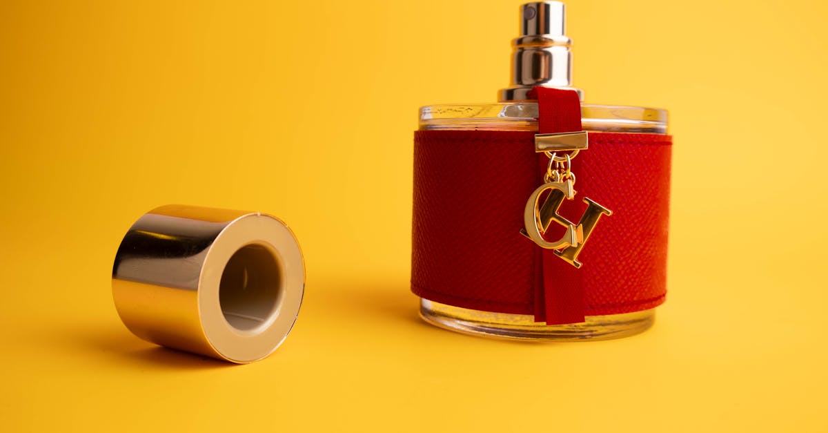 Een stijlvolle, luxe parfumfles met een rode dop en gouden accenten tegen een heldergele achtergrond.